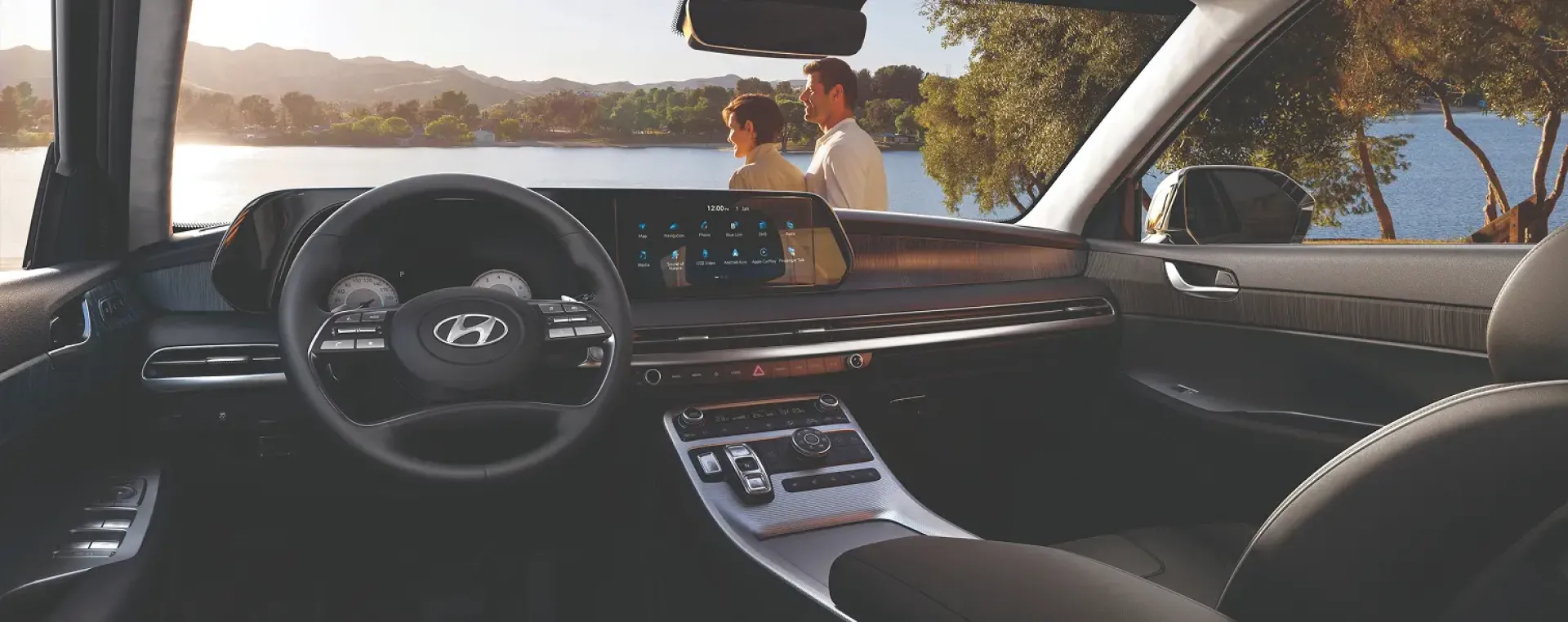 Imagen de una pareja vista desde el interior de un Palisade mostrando asi tambien el dashboard del vehiculo.
